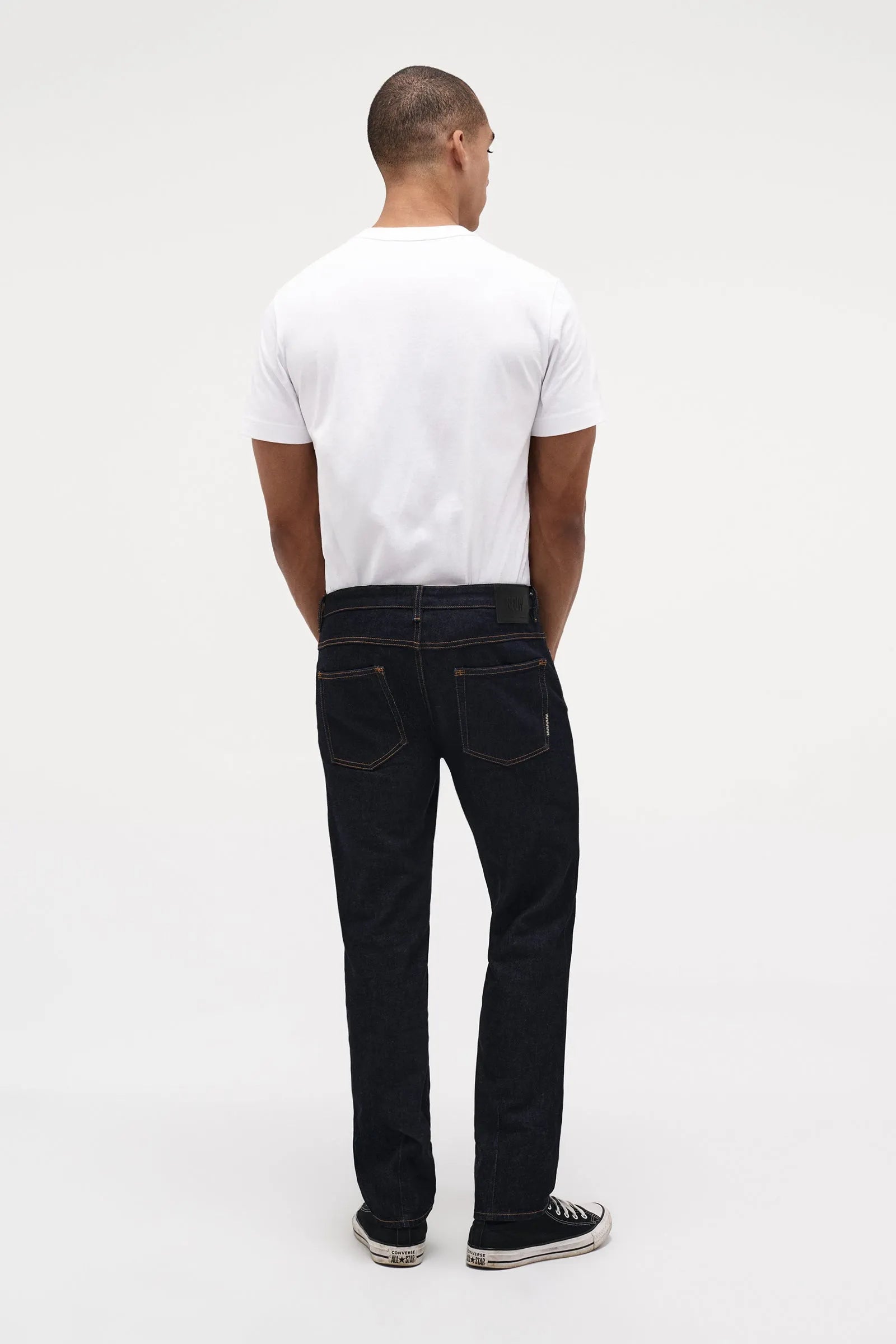 Man wearing a white t-shirt and raw jeans 