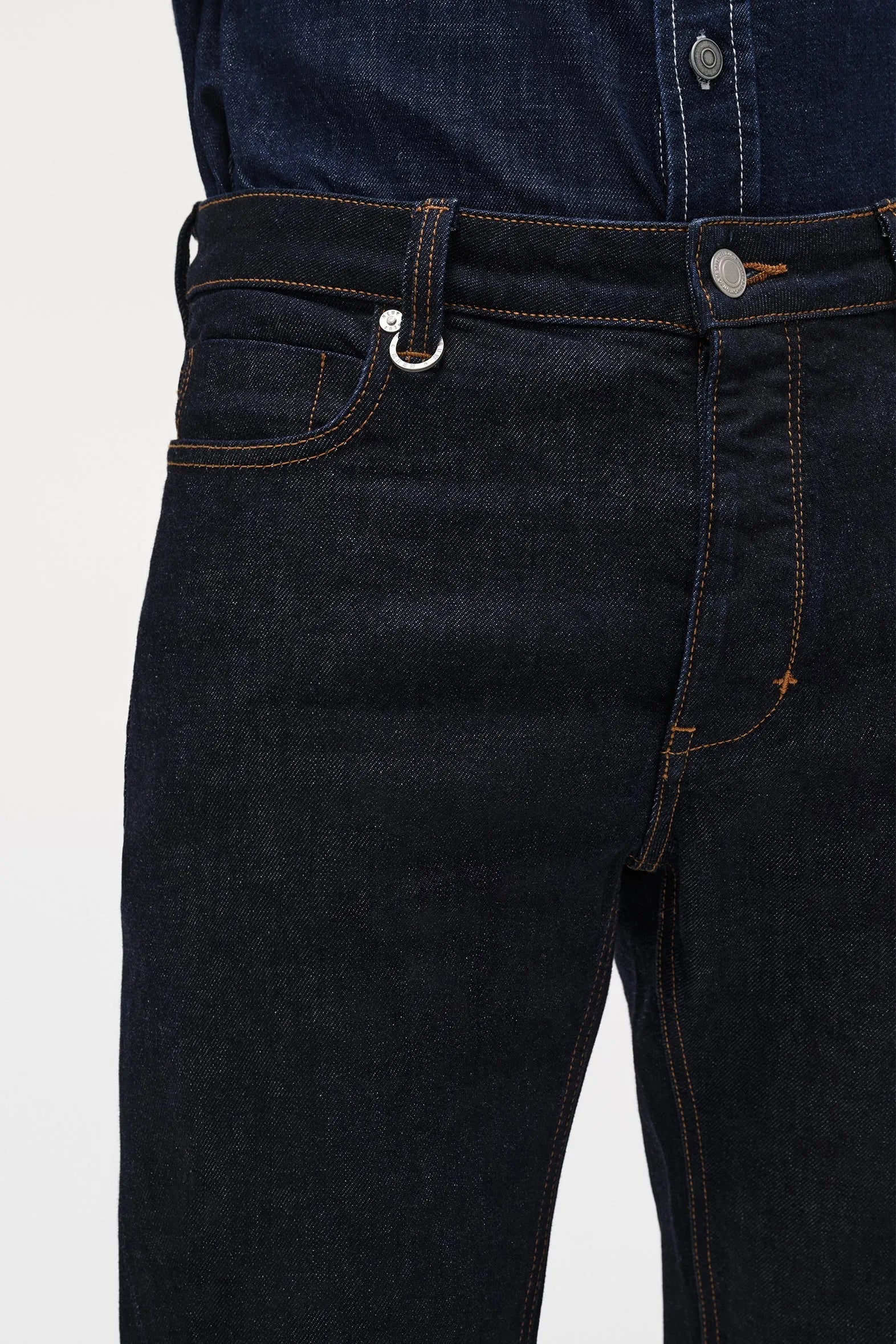 Close-up of dark blue jeans with a white background