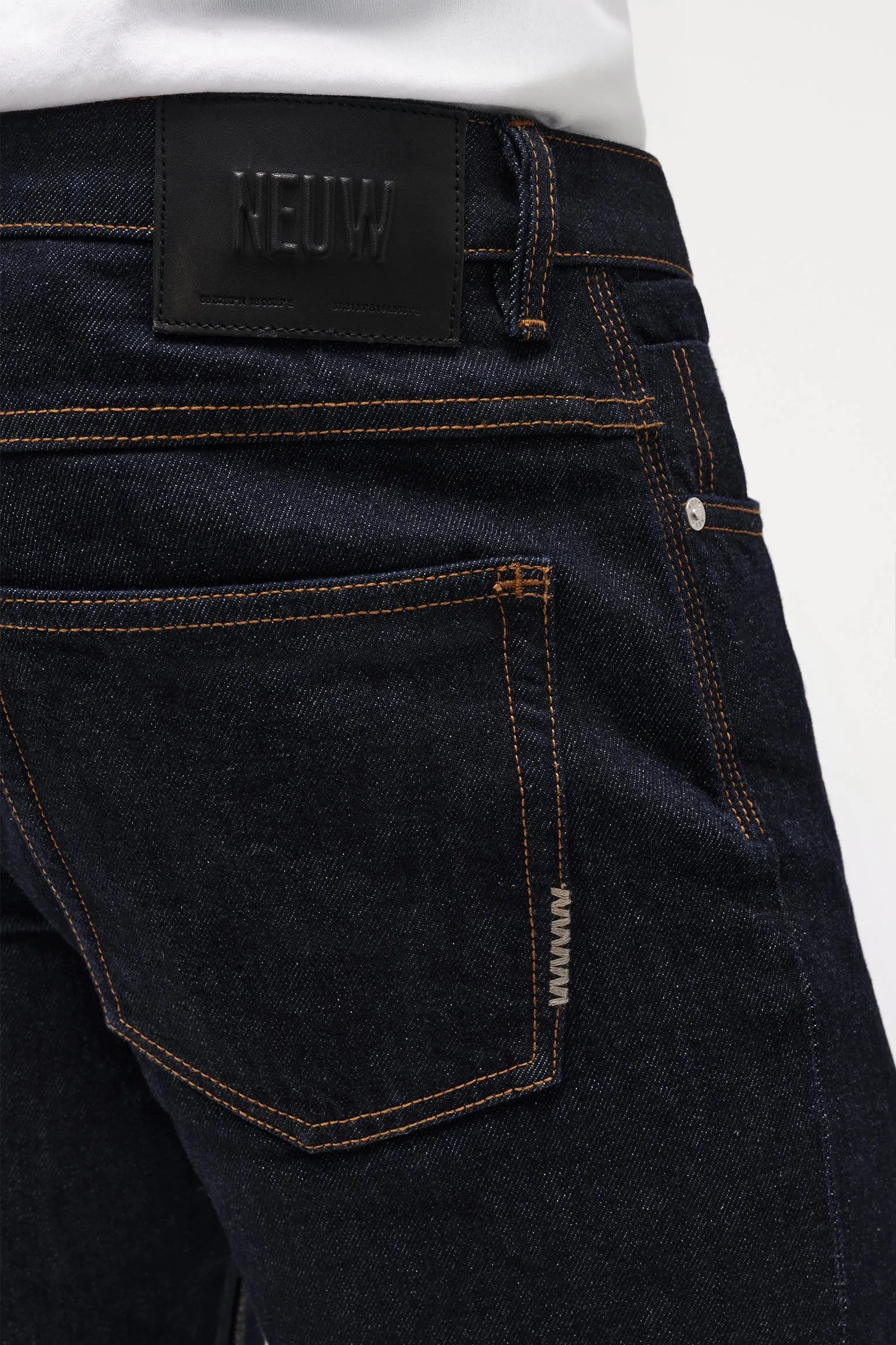 Dark blue jeans with a Neuw brand label on a white background